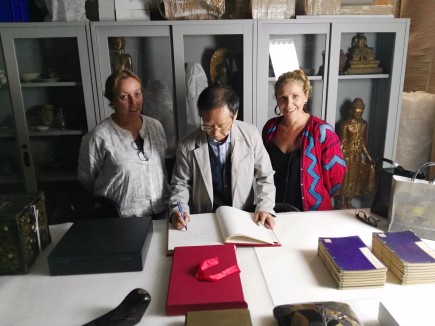 Hiromu Ozawa firmando el libro de oro del Museo junto a Carmela Gallego y Nerea Díez de Pinos